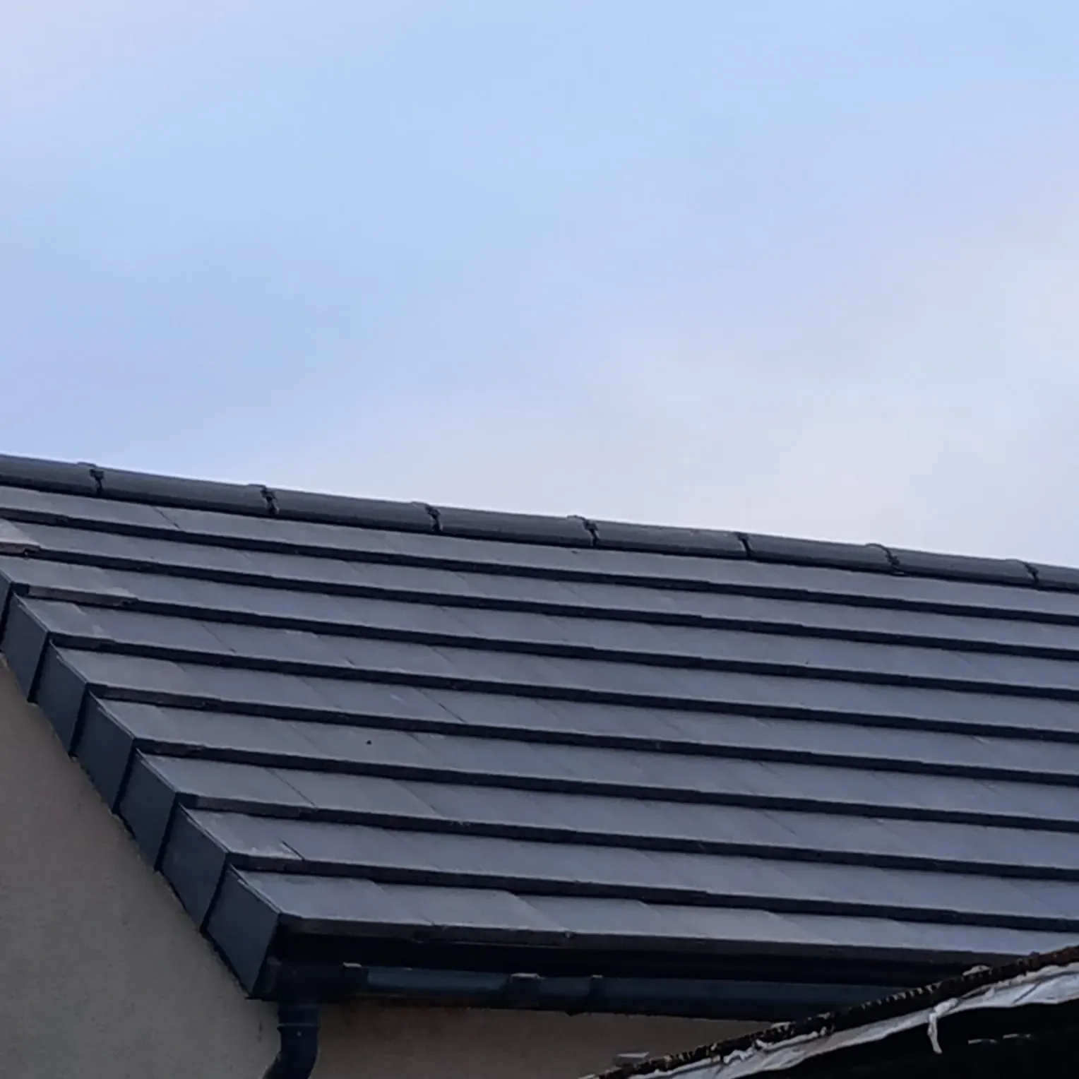 Modern dark grey tiled roof with matching fascias and guttering on a residential building in Leicestershire, showcasing quality roofing work by 5 Star Roofing Leicester.