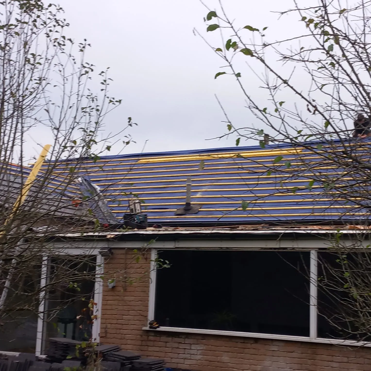 Roof replacement in progress on a Leicestershire home, showing blue underlayment and timber battens ready for new tiles.