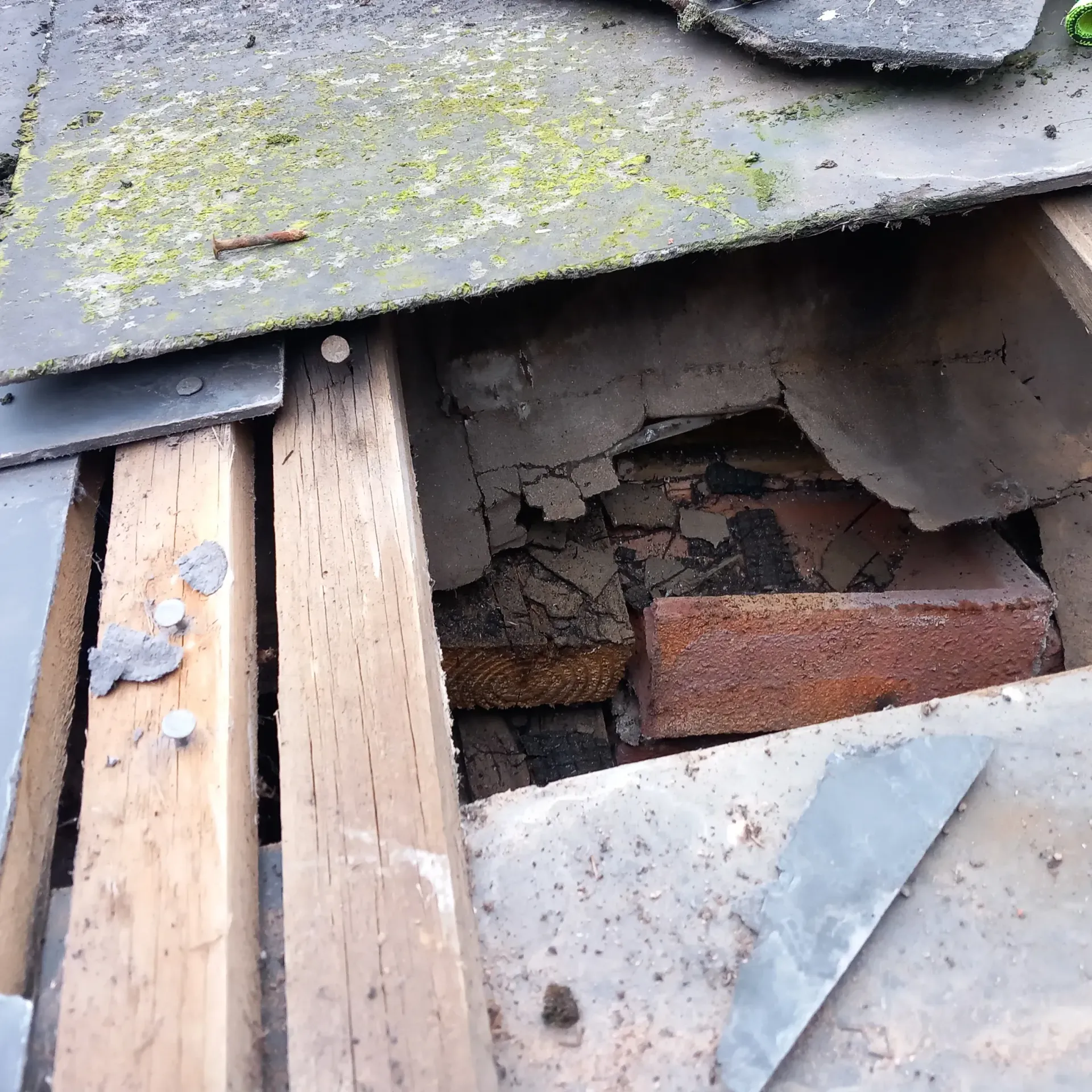 Severely damaged roof in Leicester with missing and broken slate tiles, extensive moss, exposed timber, and visible brickwork, signifying a critical need for professional roof repair or re-roofing by 5 Star Roofing Leicester.